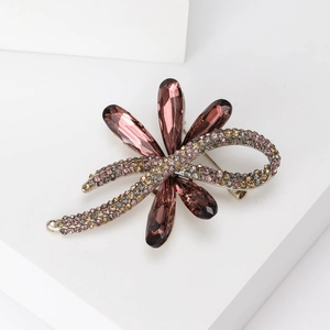 Detail of silver brooch with large purple crystals and pink rhinestones on white stand