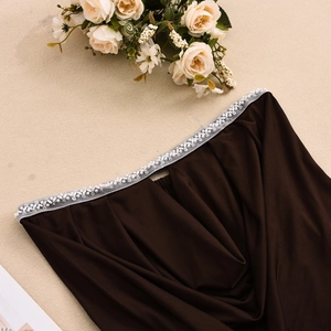 Detailopname van parel- en kraalafwerking op een donkerbruine satijnen crop top