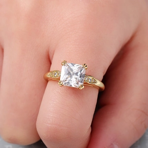 Makroaufnahme eines quadratischen Zirkonia-Rings mit goldenem Vier-Klauen-Blatt-Design