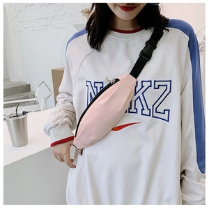 Pink canvas waist bag with black adjustable strap and buckle shown on a model