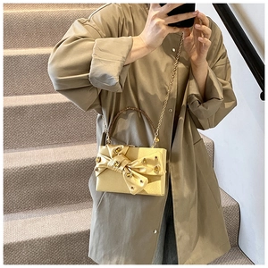 Detail of gold evening clutch bag featuring rhinestone bow and elegant metal chain strap