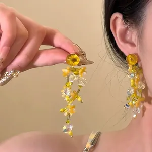 Detail of yellow flower beaded tassel earrings featuring tiered design and bohemian summer style