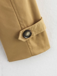 Detailansicht der khakifarbenen Trenchcoat-Ärmel mit Marmorknopf und Twill-Stoffstruktur