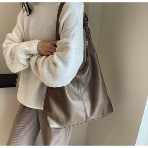 Detail of soft brown leather tote bag showing smooth texture and metallic zipper