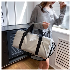 Silver fitness bag with black straps being held by a model in a minimalist indoor setting