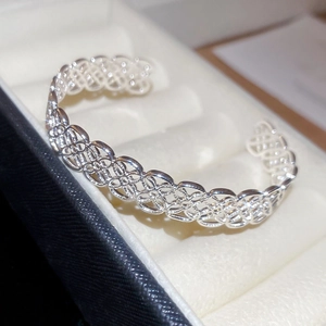 Gros plan détaillé d'un bracelet jonc argenté à motif floral évidé sur un écrin en velours