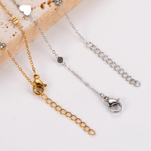 Macro detail of gold and silver anklets showing the lobster clasp and adjustable extension chain