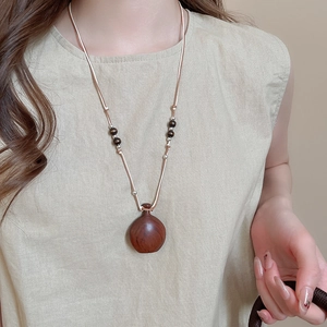 Macro detail of dark red wood bottle pendant necklace with beads on wax cord