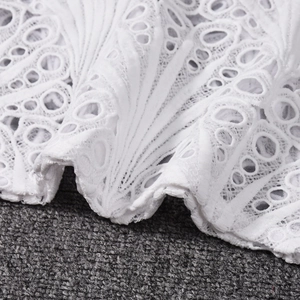 Detailaufnahme der komplizierten weißen Spitzenstickerei und der hohlen Stofftextur