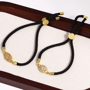 Detail of adjustable black cord bracelets with gold metal accents and zircon stones