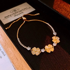 Close-up of golden zircon flower bracelet with opal stones and adjustable drawstring chain