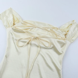 Detail eines champagnerfarbenen Satin-Abendkleides mit überkreuzter Schnürung am Rücken