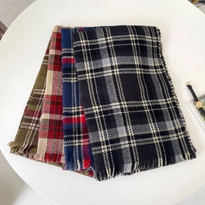 Détail de foulards à carreaux pliés en plusieurs couleurs avec de doux pompons à franges