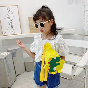 Child wearing a bright yellow nylon dinosaur crossbody chest bag with adjustable strap