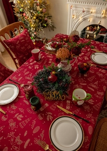 Detail of red Christmas tablecloth featuring golden HO HO HO print and festive patterns
