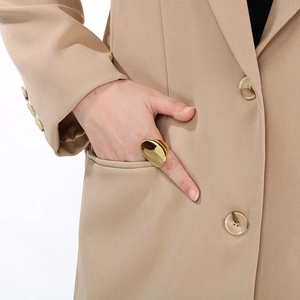 Polished golden oval stainless steel ring styled with a minimalist khaki blazer sleeve
