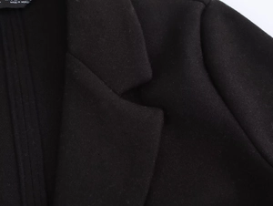 Close-up detail of black wool coat lapel with neat stitching and fabric texture