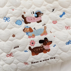 Detail of cartoon dachshund embroidery and heart quilted texture on a cream handbag