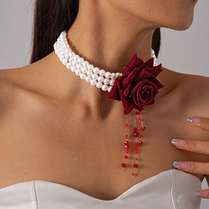 Détail d'un choker en perles triple rang avec rose en velours et glands en perles rouges
