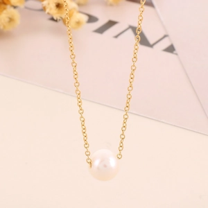 Close-up of a minimalist 18K gold plated titanium necklace featuring a white shell pearl