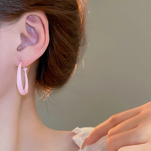 Close-up of a model wearing light pink minimalist round hoop earrings in soft warm lighting