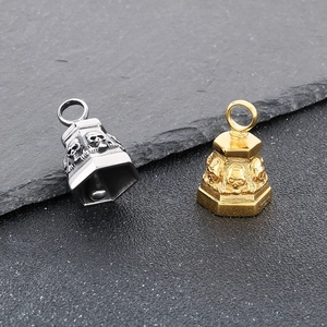 Detailed view of punk style silver and gold skull bell pendants on stone background