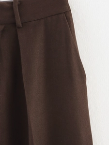 Detailed close-up of the waistband on dark brown twill trousers with reinforced loops