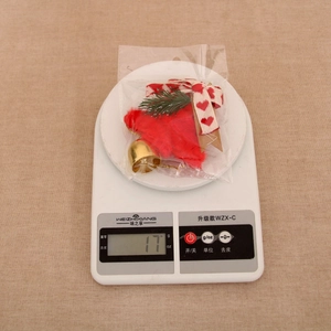 Detail of red plush Christmas bell hanger with pine needles and heart bow on scale