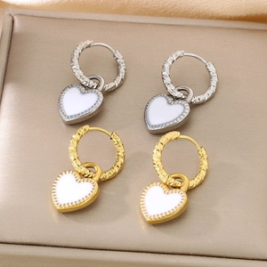 Détail de boucles d'oreilles cœur en or 18 carats avec émail blanc et texture martelée
