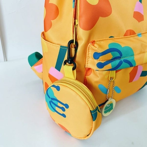 Yellow kids backpack with vibrant flower prints and round coin pouch on white background