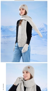 Close-up of gray knit beanie, scarf and mittens set with leather logo detail