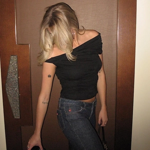 Detail showing the ruched slim fit black off-shoulder knit top with denim jeans