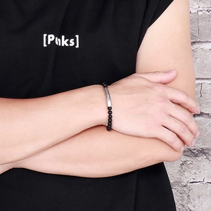 Detail of matte black onyx beads and brushed stainless steel tube on men's wrist