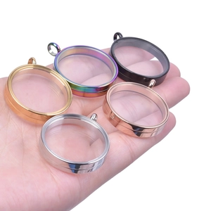 Detailed display of five color round stainless steel glass locket pendants held in hand