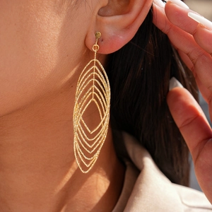 Detail shot of oversized geometric gold hollow-out clip-on earrings on a model's ear