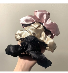 Dettaglio delle pinze per capelli in raso rosa, oro e nero con finitura lucida