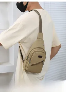 Detail of khaki canvas sling bag showing multiple zippers and adjustable sport strap
