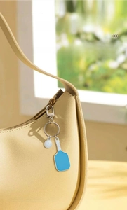 Close-up of blue pickleball paddle keychain with white ball hanging on yellow bag