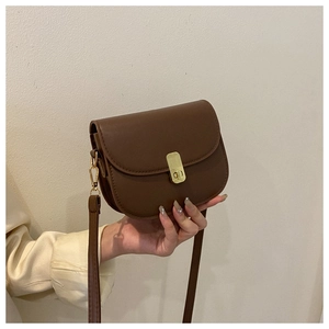 Detail of vintage brown leather saddle bag featuring a polished gold twist lock closure