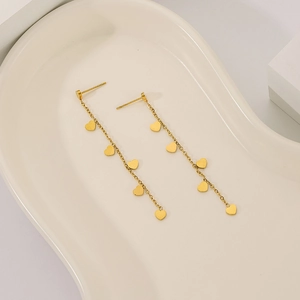 Minimalist gold heart tassel earrings with long fringe drops on a ceramic tray