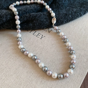 Detailed close-up of multi-colored pearls in white, grey, and lilac with a silver clasp