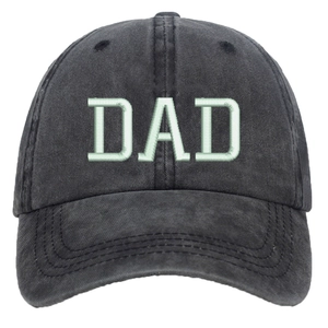 Detailed view of green DAD embroidery on washed black cotton baseball cap fabric