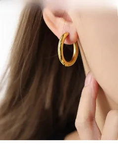 Close-up of a thick gold plated titanium hoop earring on a model for a luxury French look