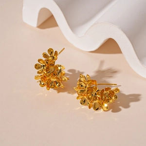Detailed view of glossy golden floral C-shaped earrings on a minimalist white prop