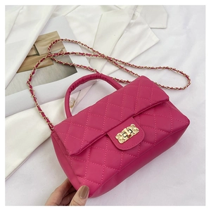 Detail of fuchsia quilted handbag with gold chain strap and metallic clasp on a white background