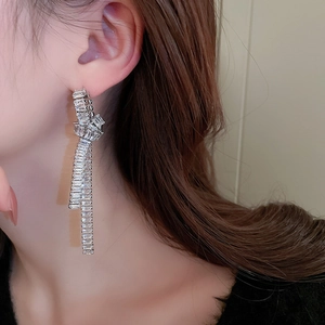 Close-up of sparkling zircon knot long tassel earrings worn by a model in silver finish