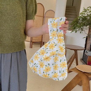 Floral cotton wrist bag held by a model in a minimalist bright indoor setting