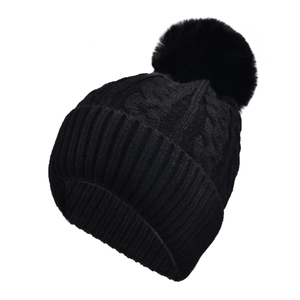 Detail view of black cable-knit beanie with fluffy pom-pom and wide ribbed cuff