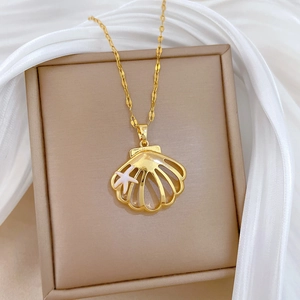 Detailed close-up of gold shell pendant with white starfish charm on soft silk