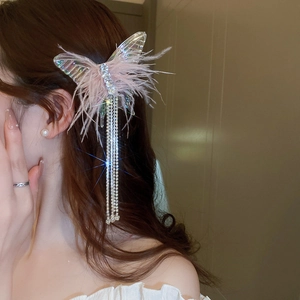 Close-up of mesh bow hair clip featuring pink feathers and long rhinestone tassels
